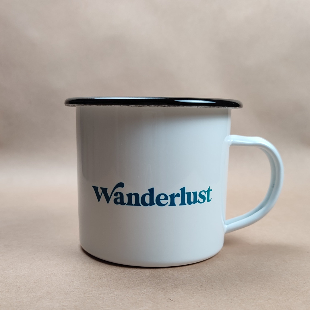 Enamel Mug - "Wanderlust" on one side and "not all those who wander are lost" printed on the other side. Printed on a white enamel mug with a blak rim. Designed and printed in Ireland.